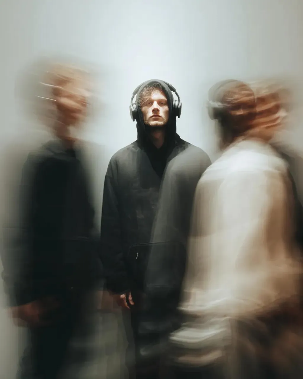 A photo of an man standing completely still, wearing headphones