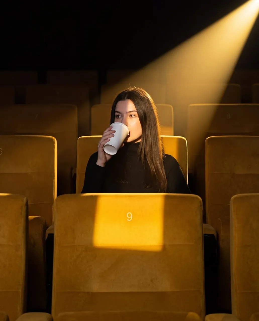 A medium shot captures a person sitting alone in an empty movie
